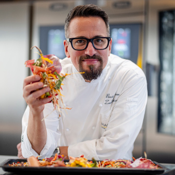 chef max zedelmeier inside the zanussi professional kitchen holding cut vegetables